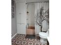 Compact bathroom featuring a shower with decorative curtain, vintage pink tub, and storage cabinet at 4300 E Bay Dr # 309, Clearwater, FL 33764