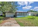 View of the home's exterior showing the attached garage, screened-in porch, and partially shaded front lawn at 4911 Bartelt Rd, Holiday, FL 34690