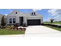 Attractive single-Gathering home featuring stone accents, a dark garage door, and nicely landscaped front yard at 5033 Chapel Row Ave, Apollo Beach, FL 33572