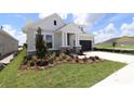 Single-Gathering home boasting stone accents, dark garage, and beautifully designed landscaping in the front yard at 5033 Chapel Row Ave, Apollo Beach, FL 33572