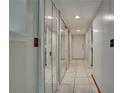 Bright hallway with mirrored closet doors, white tile flooring and recessed lighting at 6338 Newtown Cir # 38A6, Tampa, FL 33615