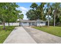 Inviting single-story home with lush green lawn, a long driveway, and mature trees at 8897 54Th N St, Pinellas Park, FL 33782