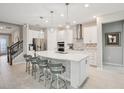 Modern kitchen with white cabinetry, stainless steel appliances, a large island, and pendant lighting at 9107 Rally Spring Loop, Wesley Chapel, FL 33545