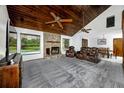 Spacious living room with a stone fireplace, beamed wood ceiling, carpeted floor, and a view of the pool at 11203 Egret Nest Ct, Riverview, FL 33569