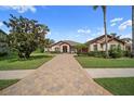Elegant home featuring manicured lawn and landscaping, stone accents, and a tile driveway at 11729 Newberry Grove Loop, Riverview, FL 33579