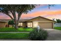 Charming single-story home with a well-manicured lawn, large tree, and attached two-car garage at 12156 Meadowbrook Ln, Largo, FL 33774