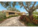Inviting single-story home with a winding driveway, mature trees, and lush landscaping at 1370 Hill Dr, Largo, FL 33770