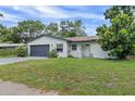 Cozy one-story home with fresh exterior paint, a gray garage door, and lush front lawn at 1586 Linwood Dr, Clearwater, FL 33755