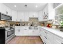 Modern kitchen with white cabinets, stainless steel appliances, mosaic backsplash, and ample counter space at 1893 Harding St, Clearwater, FL 33765