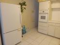Kitchen with white appliances and tile flooring, alongside white painted cabinets and countertops at 2459 Franciscan Dr # 29, Clearwater, FL 33763
