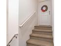 Carpeted staircase leading to the upper level, featuring a handrail and a decorative wreath on the door at 5521 Yellowfin Ct, New Port Richey, FL 34652
