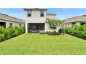 Large backyard featuring well-manicured lawn, mature landscaping, and a screened in patio at 5611 Del Coronado Dr, Apollo Beach, FL 33572