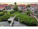 Scenic backyard featuring a private dock, manicured lawn, mature trees, and a glimpse of the home's exterior balconies at 6107 Marbella Blvd, Apollo Beach, FL 33572