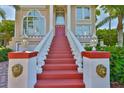 Grand entrance featuring a red staircase, ornate lamps, and lion's head details leading to a stately home with large windows at 6107 Marbella Blvd, Apollo Beach, FL 33572