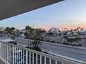 Balcony view showcases a vibrant street view with palm trees, businesses and a colorful sky at 6161 Gulf Winds Dr # 347, St Pete Beach, FL 33706
