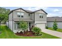 Well-maintained two-story home with a manicured lawn, colorful flowerbed, and attached two-car garage at 6248 Bradford Woods Dr, Zephyrhills, FL 33542