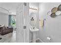 Modern powder room with a pedestal sink and decorative gold wall decor at 7124 Summer Holly Pl, Riverview, FL 33578