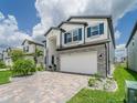 Inviting two-story home with stone accents, blue shutters, and paver driveway at 7700 Bronze Oak Dr, Wesley Chapel, FL 33545