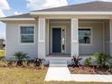 Close up of the front porch with a blue front door and meticulously landscaped surroundings at 115 White Marsh Ln, Rotonda West, FL 33947