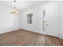 Bright living room featuring wood floors, a modern chandelier, and a window overlooking the front yard at 115 White Marsh Ln, Rotonda West, FL 33947