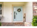Inviting entryway with a light blue front door, decorative wreath, and stylish welcome sign on a brick-paver porch at 12189 Nouveau Ave, Spring Hill, FL 34610