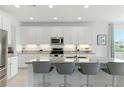 Bright, modern kitchen boasting white cabinets, granite countertops, stainless steel appliances, and a spacious center island at 12189 Nouveau Ave, Spring Hill, FL 34610
