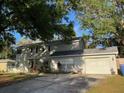 Traditional home featuring an attached two-car garage and mature landscaping at 14803 Tulip Dr, Tampa, FL 33613