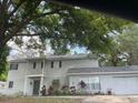 Traditional home featuring an attached two-car garage, balcony, and mature landscaping at 14803 Tulip Dr, Tampa, FL 33613