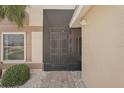 View of the front door with a security gate leading to a brick paver walkway and landscaped garden at 1901 E Del Webb Blvd, Sun City Center, FL 33573