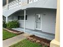 Unit exterior featuring a covered porch, concrete tiles, and brick-lined garden beds at 2410 Franciscan Dr # 18, Clearwater, FL 33763