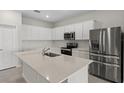 Bright kitchen featuring white cabinets, stainless steel appliances, and a large center island at 2589 Winding Creek Trl, North Port, FL 34289