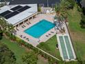 Aerial view of a community pool, shuffleboard, and lounge chairs in lush landscaped area at 2617 Cove Cay Dr # 707, Clearwater, FL 33760