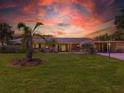 Charming single-story home with lush lawn and mature palms, bathed in a dramatic sunset at 3944 49Th S Ave, St Petersburg, FL 33711