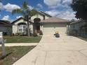 Inviting single-story home with a red front door, a two-car garage, and a lush front yard with mature landscaping at 4436 Horseshoe Pick Ln, Valrico, FL 33594