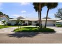 Beautiful exterior view of a well-maintained one-story home, enhanced by palm trees and a circular driveway at 5884 51St S St, St Petersburg, FL 33715
