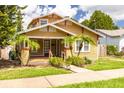 Charming home featuring a cozy front porch, well-maintained lawn, and lush landscaping with mature trees at 6408 N Central Ave, Tampa, FL 33604