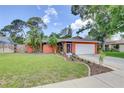 Single-story house with lush grass, tropical landscaping, sidewalk and a white two car garage door at 6865 Circle Creek Dr, Pinellas Park, FL 33781