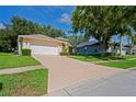 Home exterior featuring a long driveway leading to a two-car garage and well-maintained landscaping at 11412 Alden Ct, Hudson, FL 34667