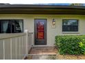 Charming front entryway with a bright red door, decorative plants, and traditional exterior lighting at 140 Dale Pl, Oldsmar, FL 34677