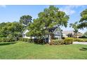 Landscaped home exterior highlighting the lush green lawn, mature trees, and meticulously maintained shrubbery at 2182 Trevor Rd, Palm Harbor, FL 34683