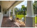 Inviting covered porch area with brick flooring and decorative chairs overlooking a well manicured, fenced backyard at 321 Barbara Cir, Belleair, FL 33756
