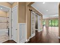 Entryway features rich wood floors, barn doors, and views of a luxurious bathroom and backyard at 3214 Forsythia Dr, Odessa, FL 33556
