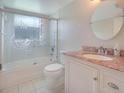 Bathroom features a granite countertop, round mirror, and tiled shower at 5390 Magnolia N Trl, Pinellas Park, FL 33782