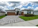 Inviting home featuring a two-car garage, brick accents, and manicured landscaping at 8749 Drummer Plank Dr, Wesley Chapel, FL 33545