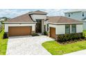 Inviting home featuring a two-car garage, brick accents, and manicured landscaping at 8749 Drummer Plank Dr, Wesley Chapel, FL 33545