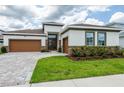 Inviting home featuring a two-car garage, brick accents, and manicured landscaping at 8749 Drummer Plank Dr, Wesley Chapel, FL 33545
