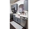 Updated kitchen with gray cabinets, stainless steel appliances, and a farmhouse sink under an arched pass-through window at 1006 Harvest Moon Dr, Seffner, FL 33584