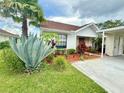 Attractive single-story home showcasing lush landscaping, including a large agave plant, and a convenient carport at 10636 Millriver Dr, New Port Richey, FL 34654