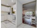 Bright kitchen featuring white cabinets, tile floor, and a view into the living area at 11485 Oakhurst Rd # 310, Largo, FL 33771