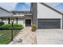 Welcoming entrance with brick accents, a dark garage door, and a paved walkway at 1222 Rainbrook Cir, Valrico, FL 33596